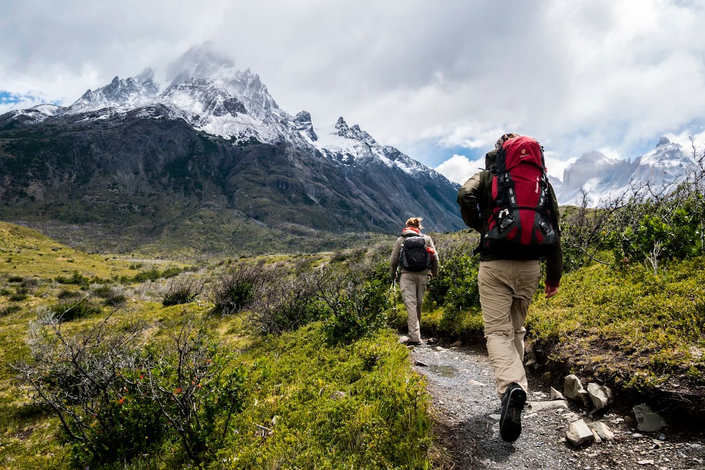 Dos excursionistas con mochilas recorren un sendero de montaña